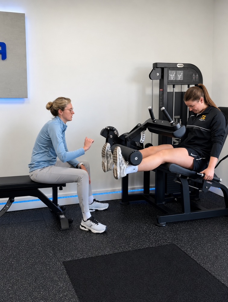 Tilly coaching a patient on a leg extension machine