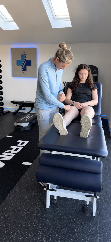 Tilly assessing a patient's knee on the treatment table